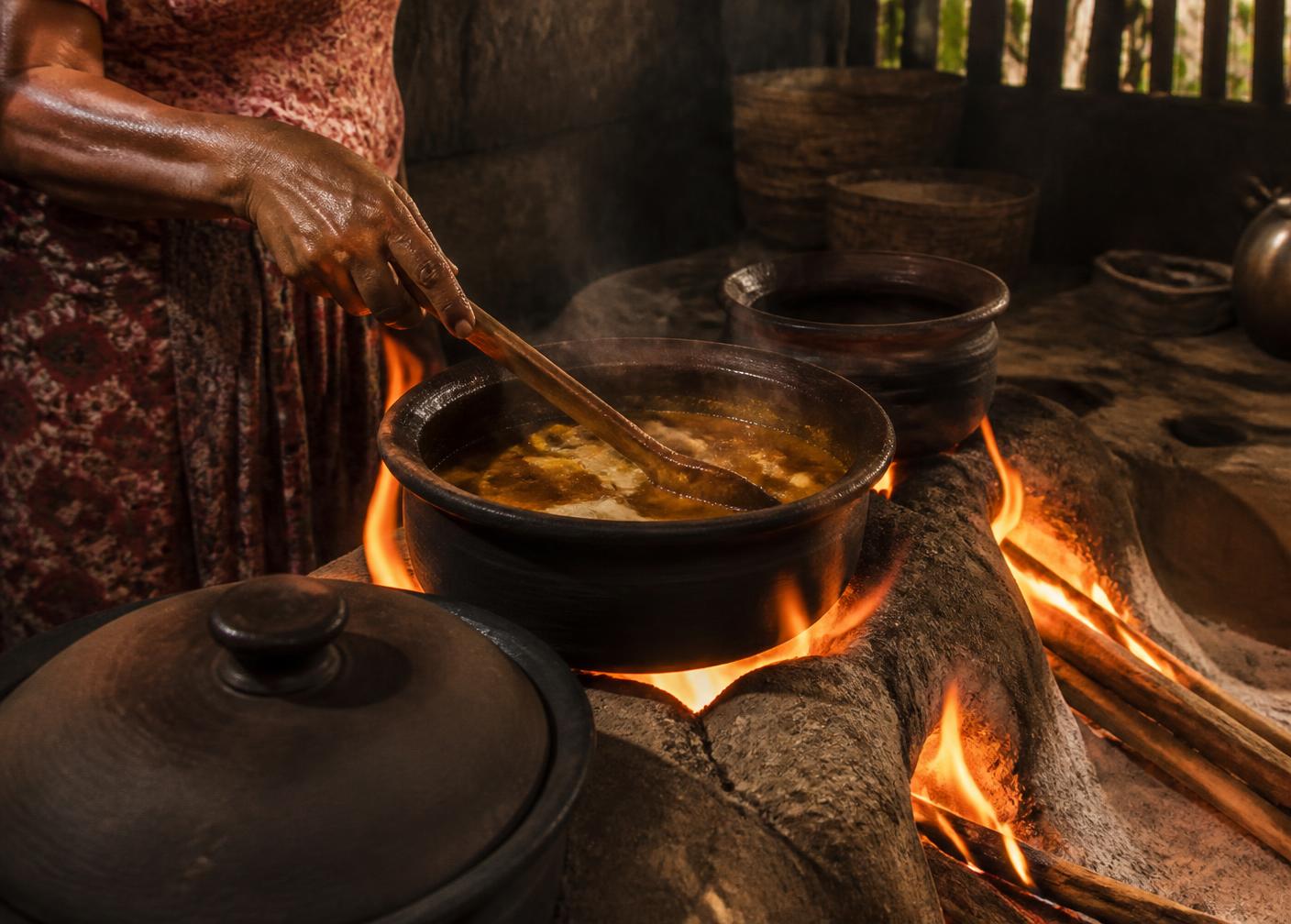 Curry simmering in a clay pot over a wood fire